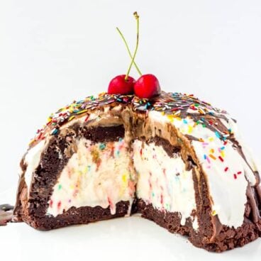 Ice Cream Brownie Mountain: A fun new ice cream cake! Rich, fudgy brownies filled with homemade ice cream (or use store bough and keep it simple!) and topped with chocolate ganache, whipped cream, chocolate sauce and sprinkles -- the perfect cake for a birthday or celebration! Change up the ice cream flavors to suit your tastes! www.thereciperebel.com