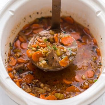 ladle scooping beef barley soup from crockpot
