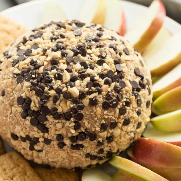 This Snickers Cheese Ball is an easy appetizer, snack or dessert -- filled with cream cheese, peanut butter, caramel and chocolate it is the BEST with apple slices! Perfect for potlucks.